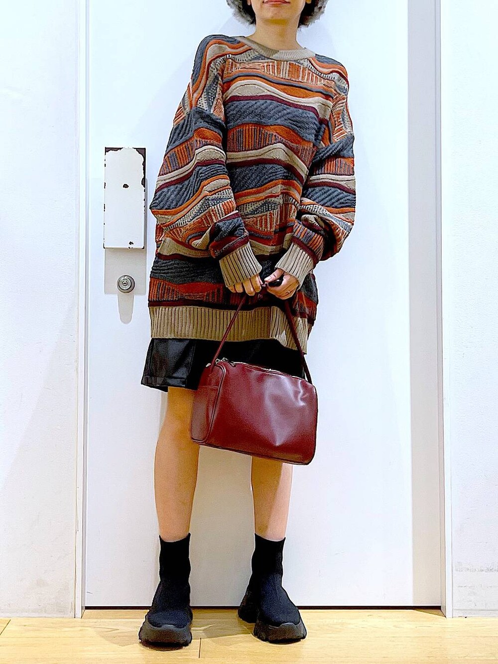 レッド系のショルダーバッグ、ブラック系のブーツ、ブラック系のその他パンツを着用したレディースの冬コーディネートの6枚目の写真