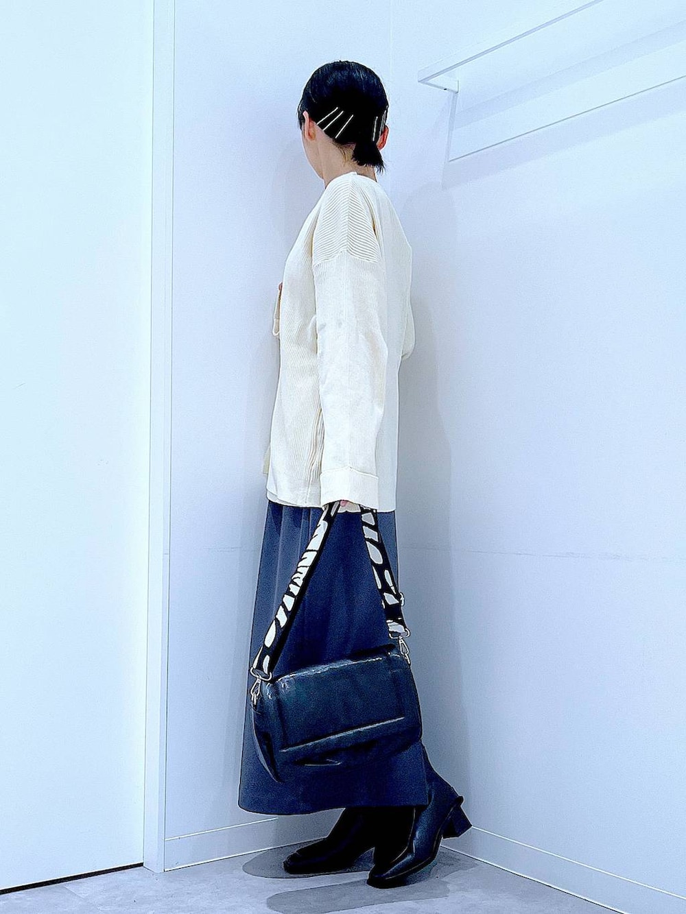 グレー系のスカート、ブラック系のショルダーバッグ、ブラック系のブーツを着用したレディースの冬コーディネートの3枚目の写真