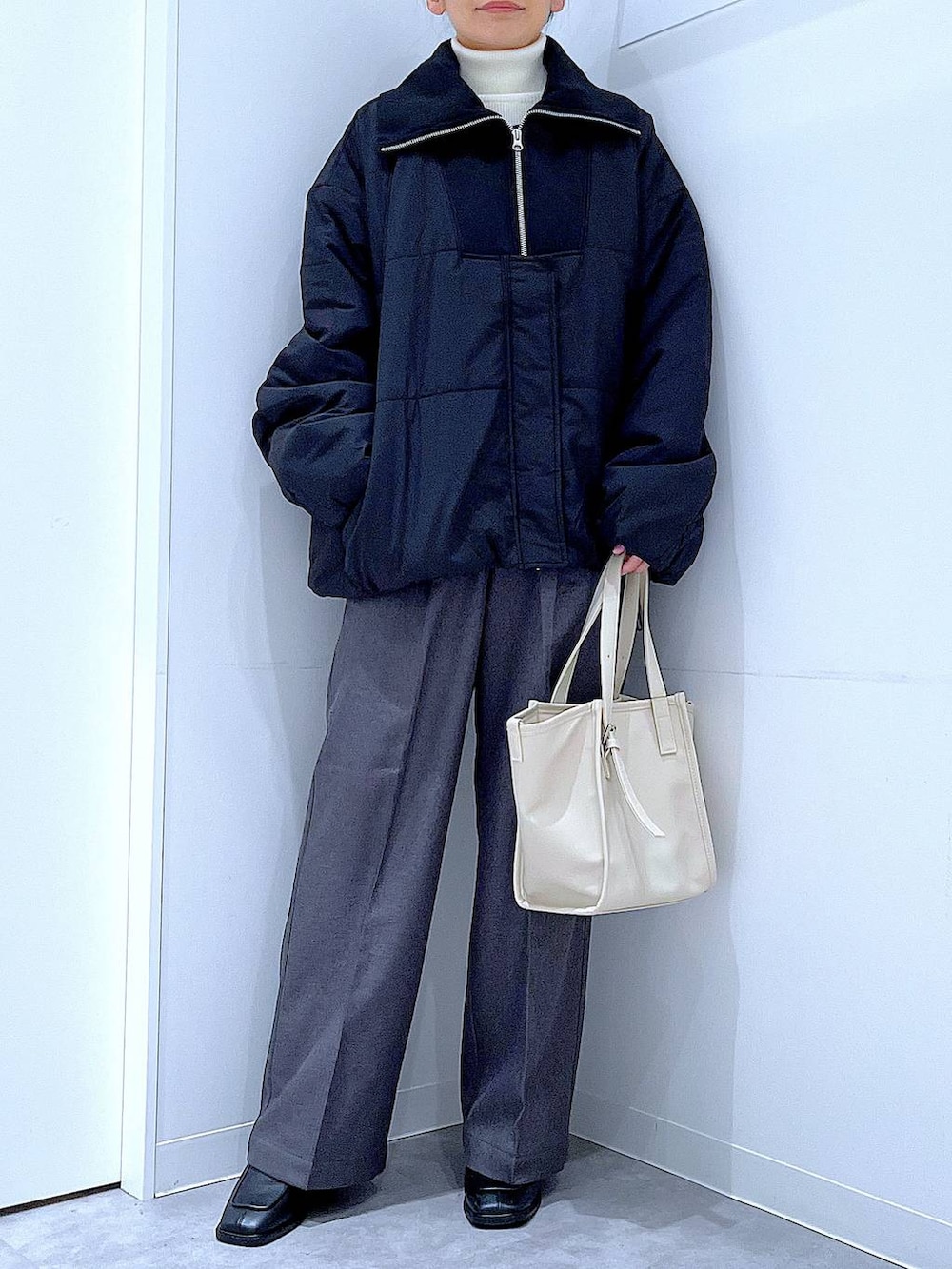 ブラック系のブルゾン、ブラック系のブーツ、グレー系のスラックスを着用したレディースの冬コーディネートの6枚目の写真