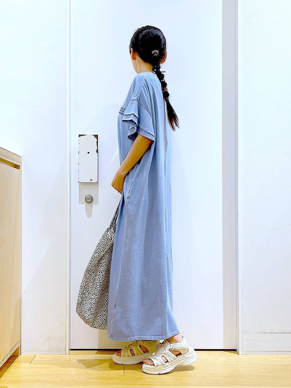 ホワイト系のサンダル、ベージュ系のトートバッグ、ブルー系のワンピースを着用したレディースの夏コーディネートの3枚目の写真