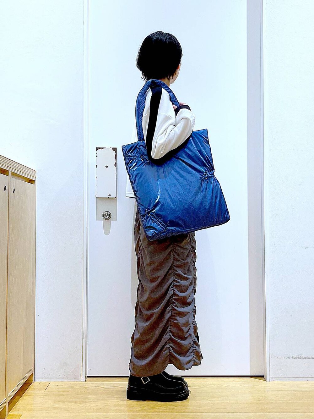 ブラック系のブーツ、ブルー系のトートバッグ、ホワイト系のTシャツ/カットソーを着用したレディースの秋コーディネートの4枚目の写真