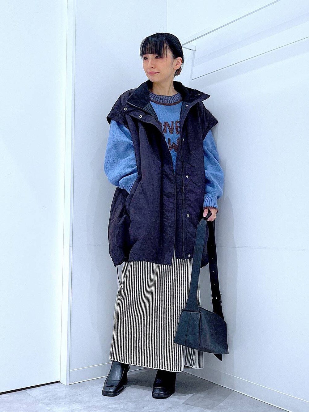 ブラック系のブルゾン、ベージュ系のスカート、ブラック系のブーツを着用したレディースの冬コーディネートの2枚目の写真