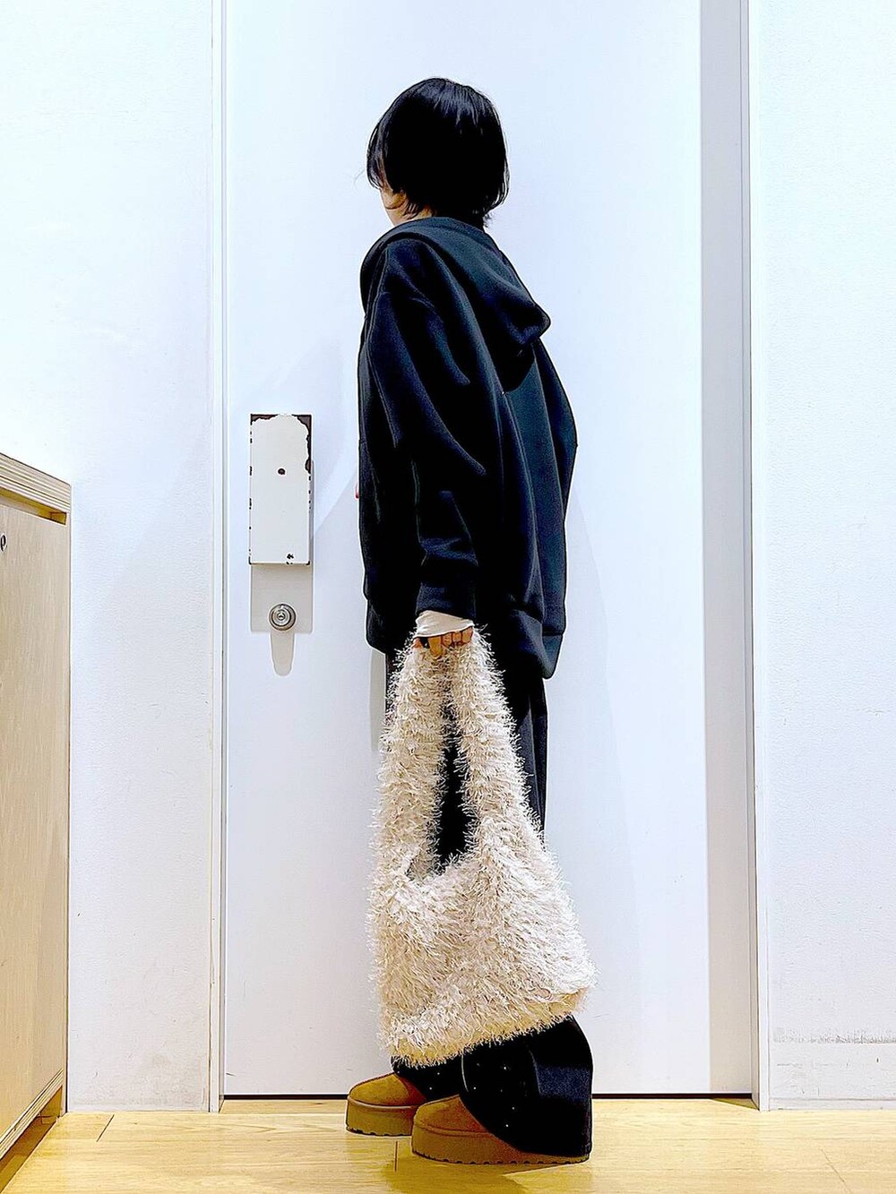 ベージュ系のスリッポン、ベージュ系のショルダーバッグ、ブラック系のデニムパンツを着用したレディースの冬コーディネートの3枚目の写真