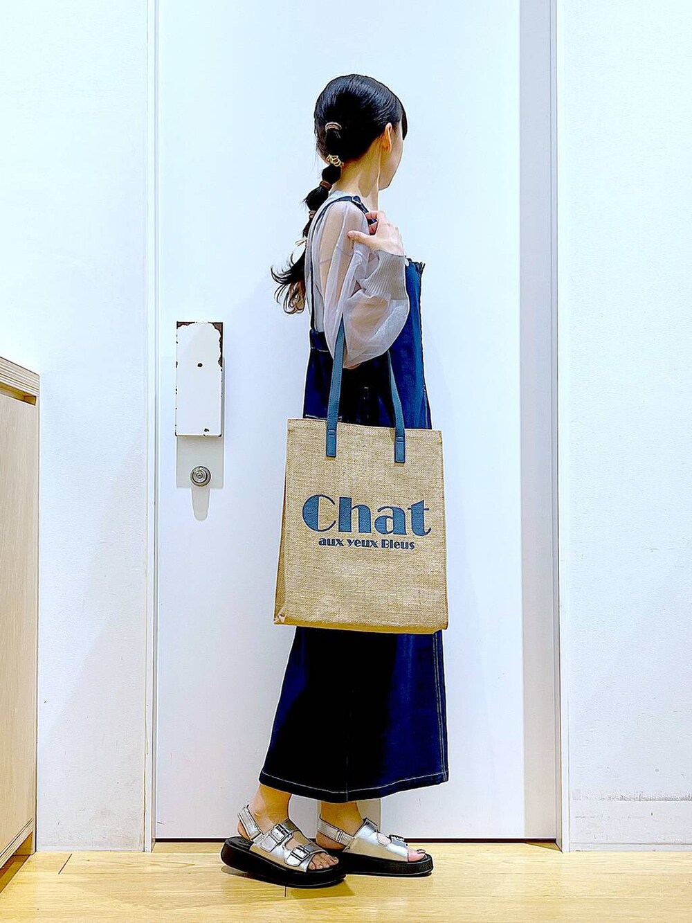 ブルー系のジャンパースカート、ブルー系のトートバッグ、シルバー系のサンダルを着用したレディースの夏コーディネートの4枚目の写真