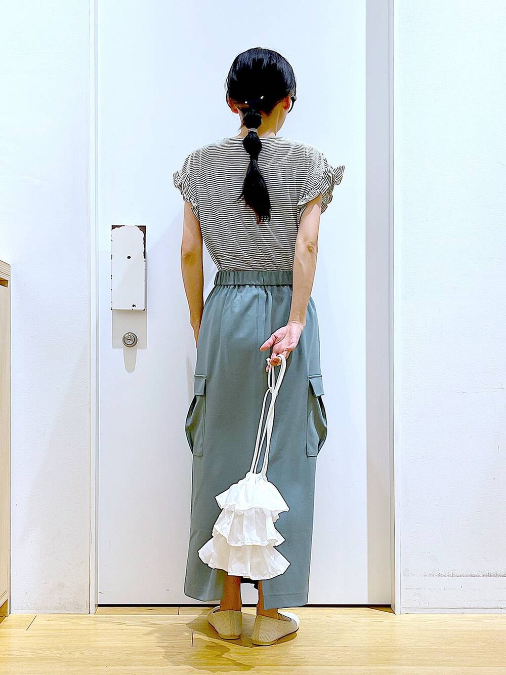 ホワイト系のショルダーバッグ、ホワイト系のパンプス、グリーン系のスカートを着用したレディースの春コーディネートの5枚目の写真