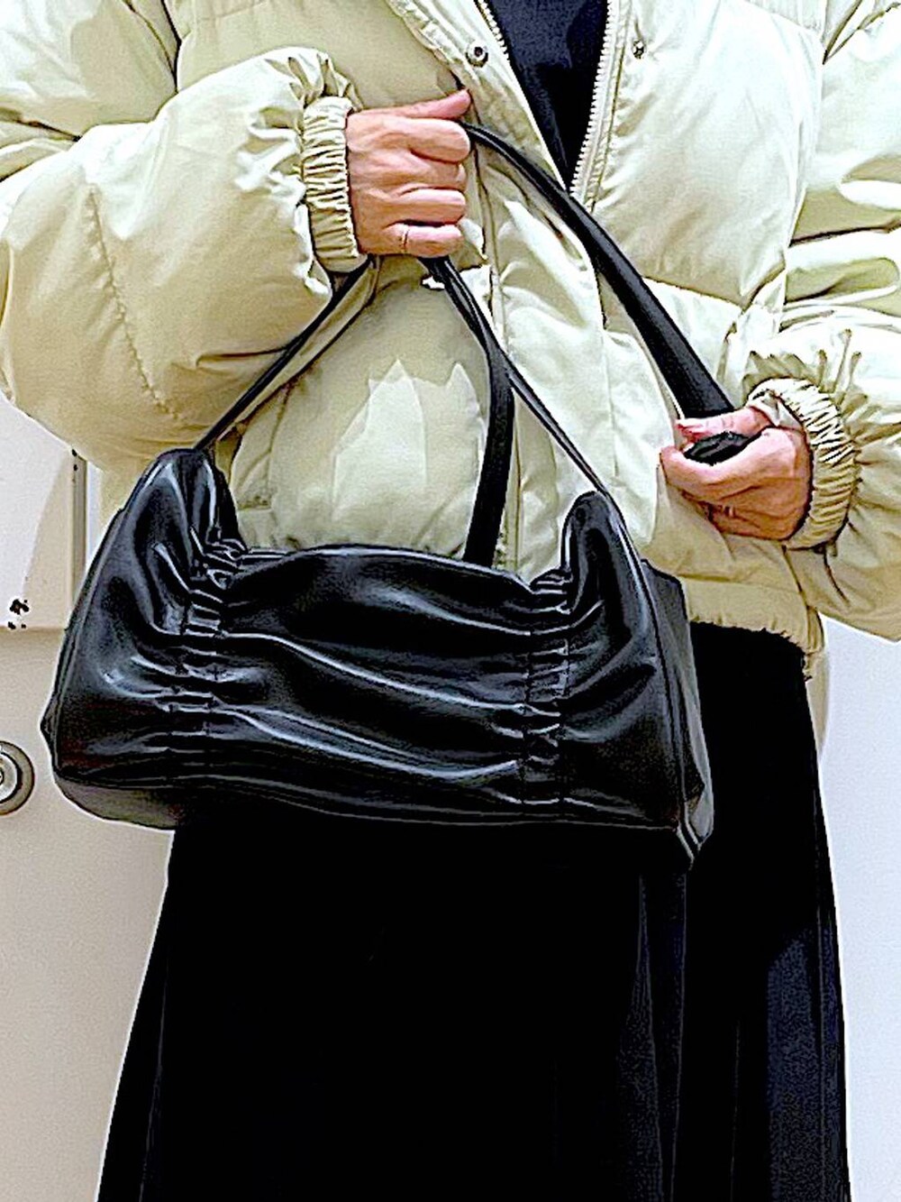 イエロー系のブルゾン、ブラック系のブーツ、ブラック系のスカートを着用したレディースの冬コーディネートの9枚目の写真