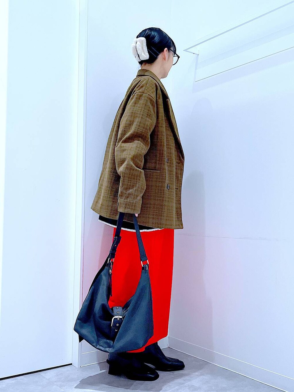 レッド系のスカート、ブラック系のブーツ、ブラック系のショルダーバッグを着用したレディースの冬コーディネートの4枚目の写真