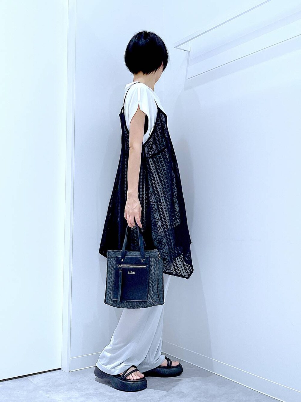 ブラック系のショルダーバッグ、ブラック系のサンダル、ホワイト系のTシャツ/カットソーを着用したレディースの夏コーディネートの4枚目の写真