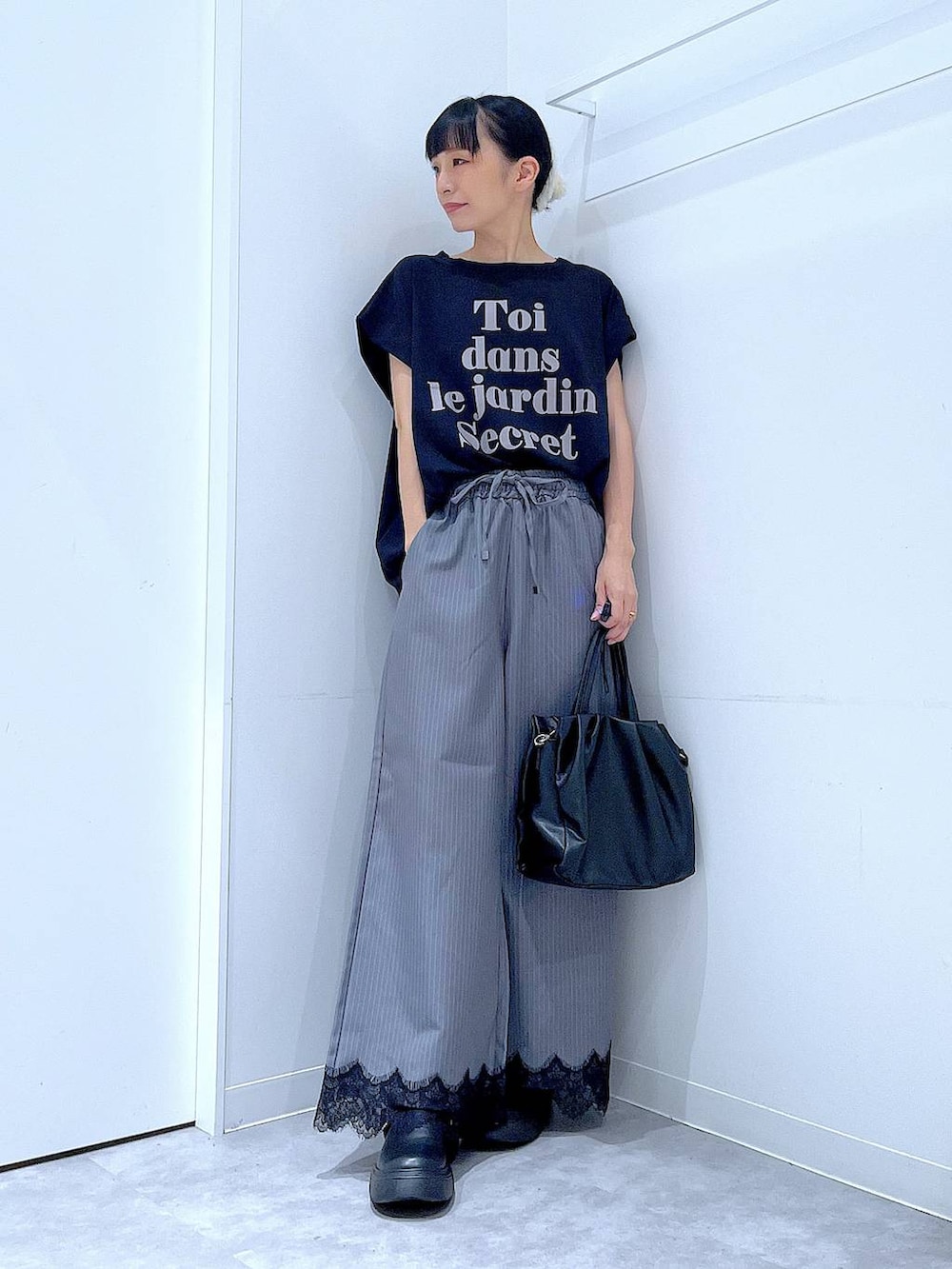 ブラック系のTシャツ/カットソー、グレー系のスラックス、ブラック系のハンドバッグを着用したレディースの秋コーディネートの2枚目の写真