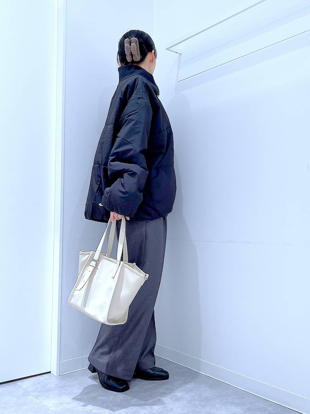 ブラック系のブルゾン、ブラック系のブーツ、グレー系のスラックスを着用したレディースの冬コーディネートの4枚目の写真