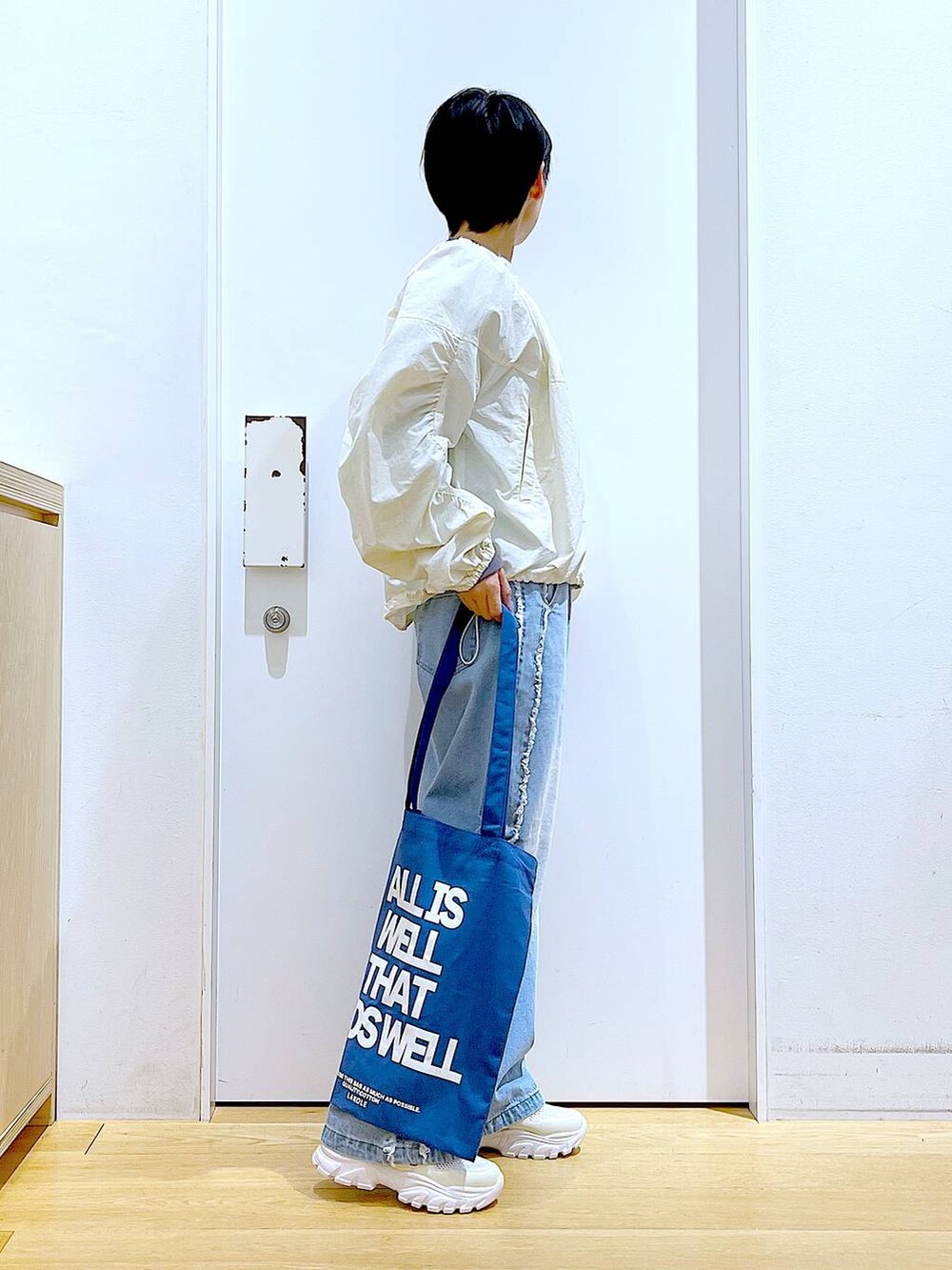 ホワイト系のスニーカー、ブルー系のデニムパンツ、ホワイト系のブルゾンを着用したレディースの春コーディネートの4枚目の写真