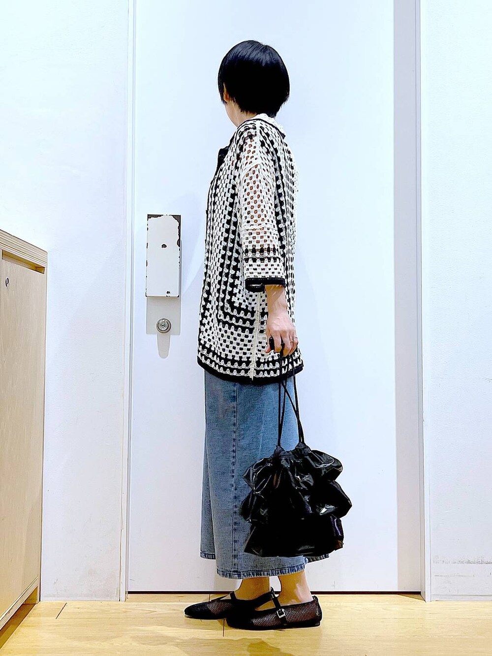 ブラック系のショルダーバッグ、ブラック系のパンプス、ブルー系のジャンパースカートを着用したレディースの春コーディネートの3枚目の写真