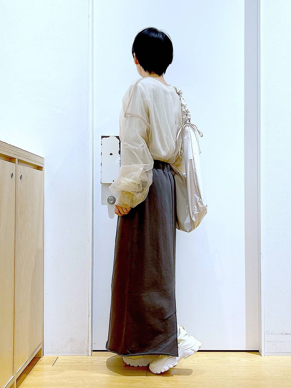 ホワイト系のショルダーバッグ、ホワイト系のスニーカー、グレー系のスカートを着用したレディースの春コーディネートの3枚目の写真