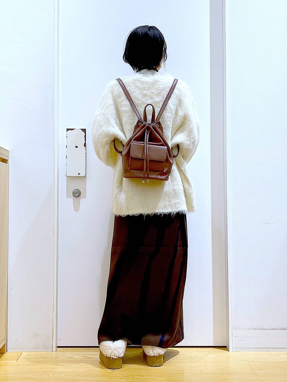 ベージュ系のニット/セーター、ブラウン系のバックパック/リュック、ブラウン系のスカートを着用したレディースの冬コーディネートの5枚目の写真