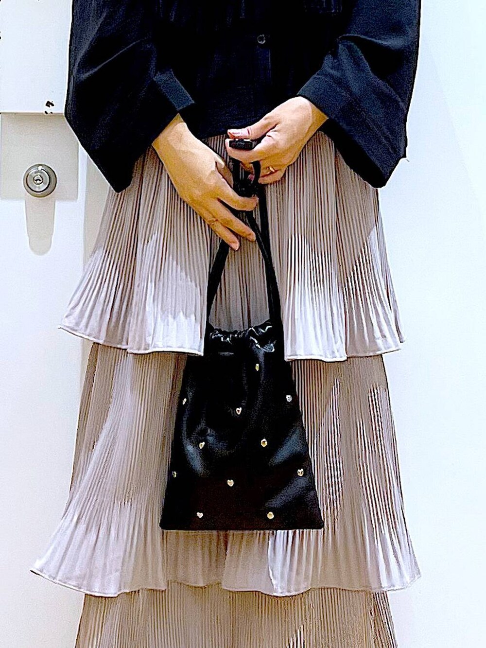 グレー系のスカート、ブラック系のショルダーバッグ、ブラック系のパンプスを着用したレディースの秋コーディネートの9枚目の写真