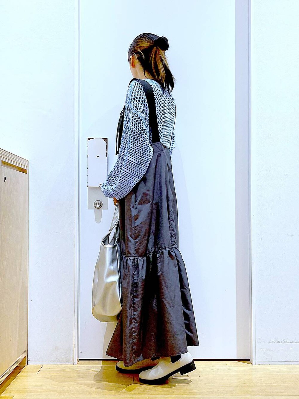 ブラック系のTシャツ/カットソー、ブルー系のニット/セーター、シルバー系のトートバッグを着用したレディースの春コーディネートの3枚目の写真