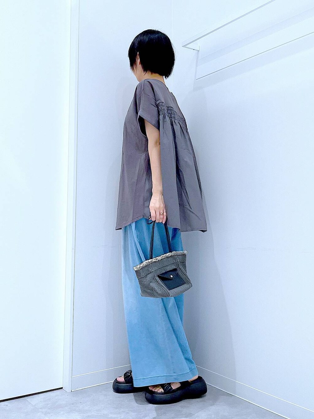 ブラック系のショルダーバッグ、ブラック系のサンダル、ブルー系のデニムパンツを着用したレディースの夏コーディネートの3枚目の写真