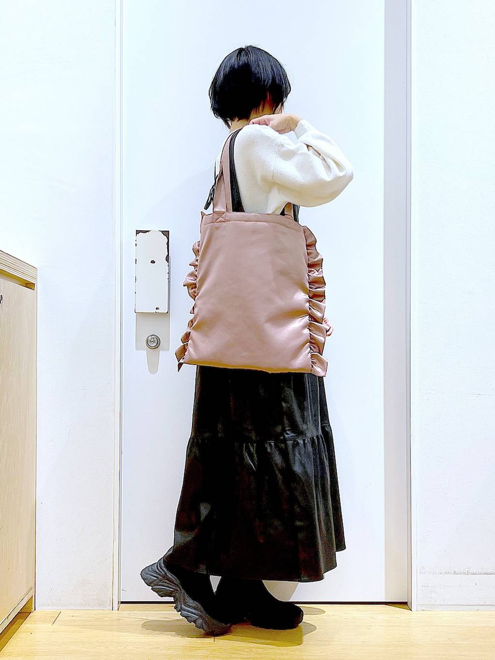 ブラック系のブーツ、ブラック系のワンピース、ピンク系のトートバッグを着用したレディースの冬コーディネートの4枚目の写真