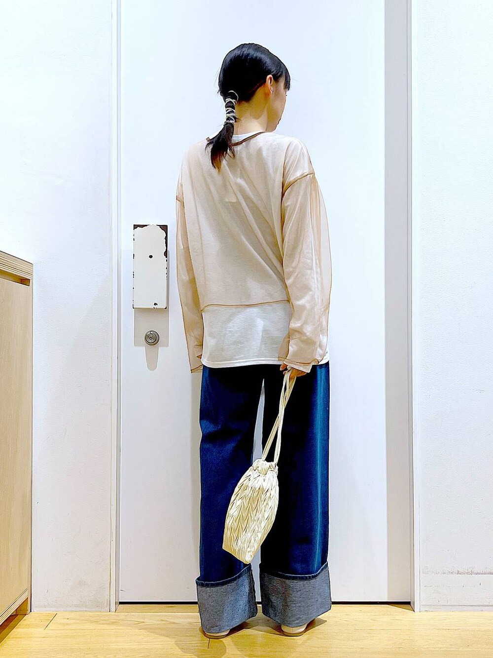 ホワイト系のショルダーバッグ、ホワイト系のパンプス、ブルー系のデニムパンツを着用したレディースの秋コーディネートの5枚目の写真