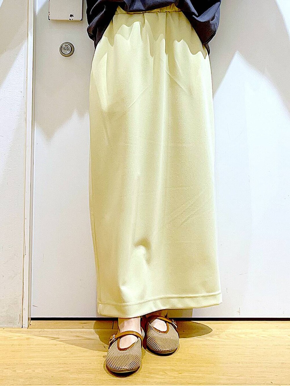 ホワイト系のショルダーバッグ、ベージュ系のパンプス、イエロー系のスカートを着用したレディースの夏コーディネートの8枚目の写真