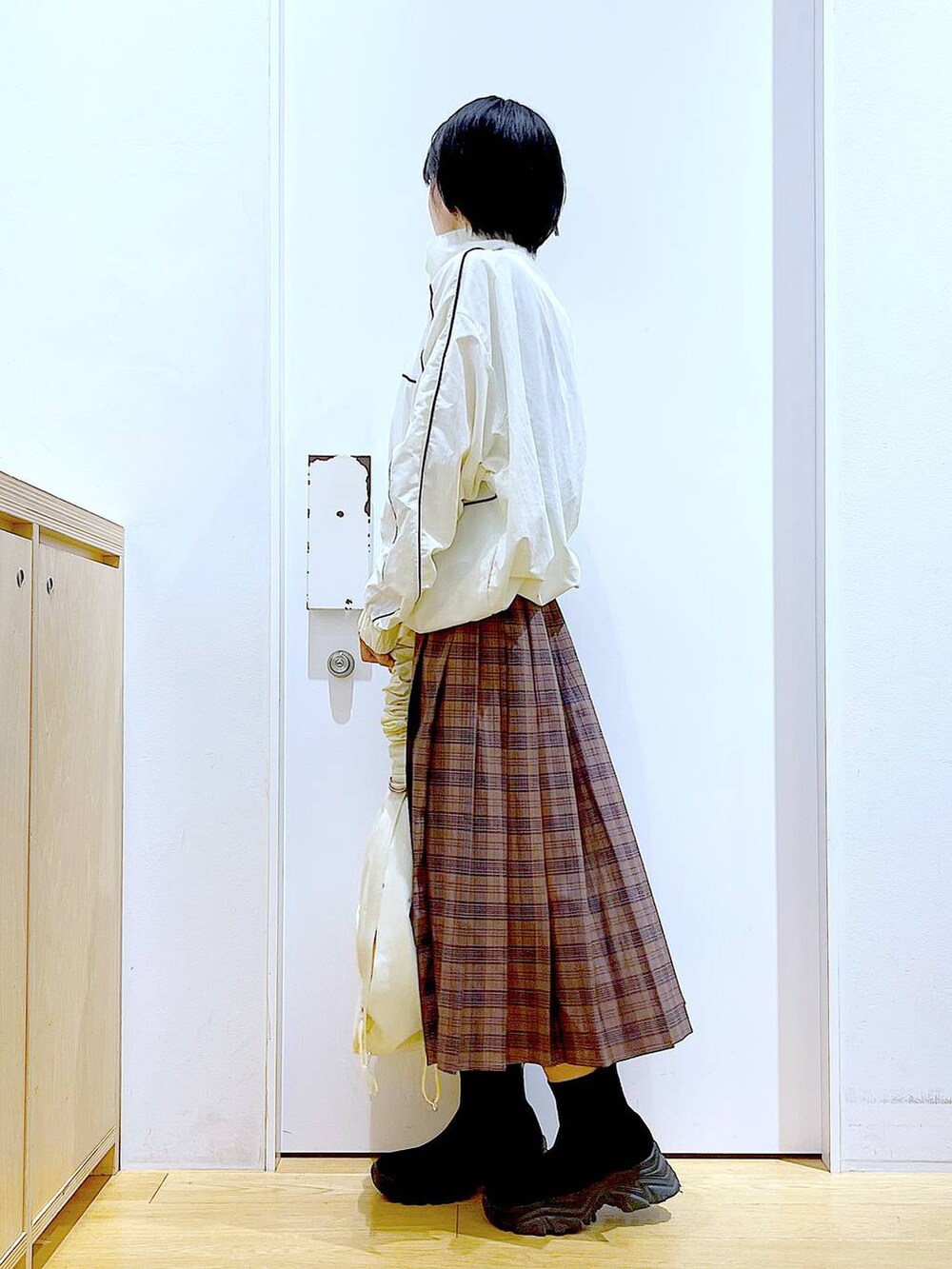 ホワイト系のショルダーバッグ、ベージュ系のブルゾン、ブラック系のブーツを着用したレディースの秋コーディネートの3枚目の写真