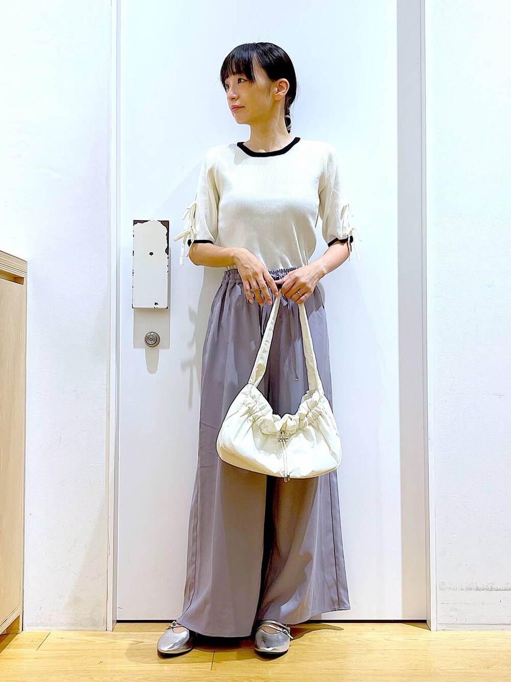 ホワイト系のハンドバッグ、グレー系のその他パンツ、シルバー系のパンプスを着用したレディースの秋コーディネートの2枚目の写真