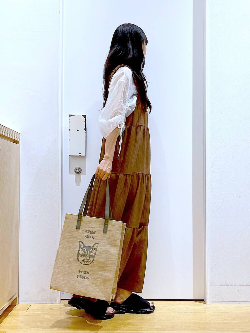 ブラック系のサンダル、ベージュ系のワンピース、グレー系のトートバッグを着用したレディースの夏コーディネートの4枚目の写真