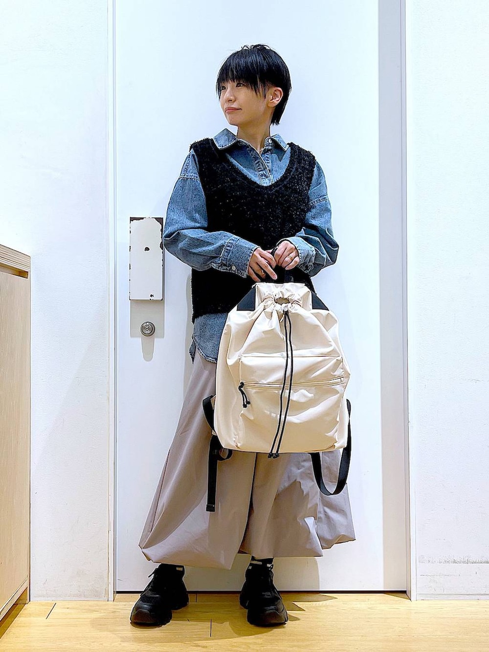 ブルー系のシャツ/ブラウス、ブラック系のスニーカー、ホワイト系のバックパック/リュックを着用したレディースの春コーディネートの2枚目の写真