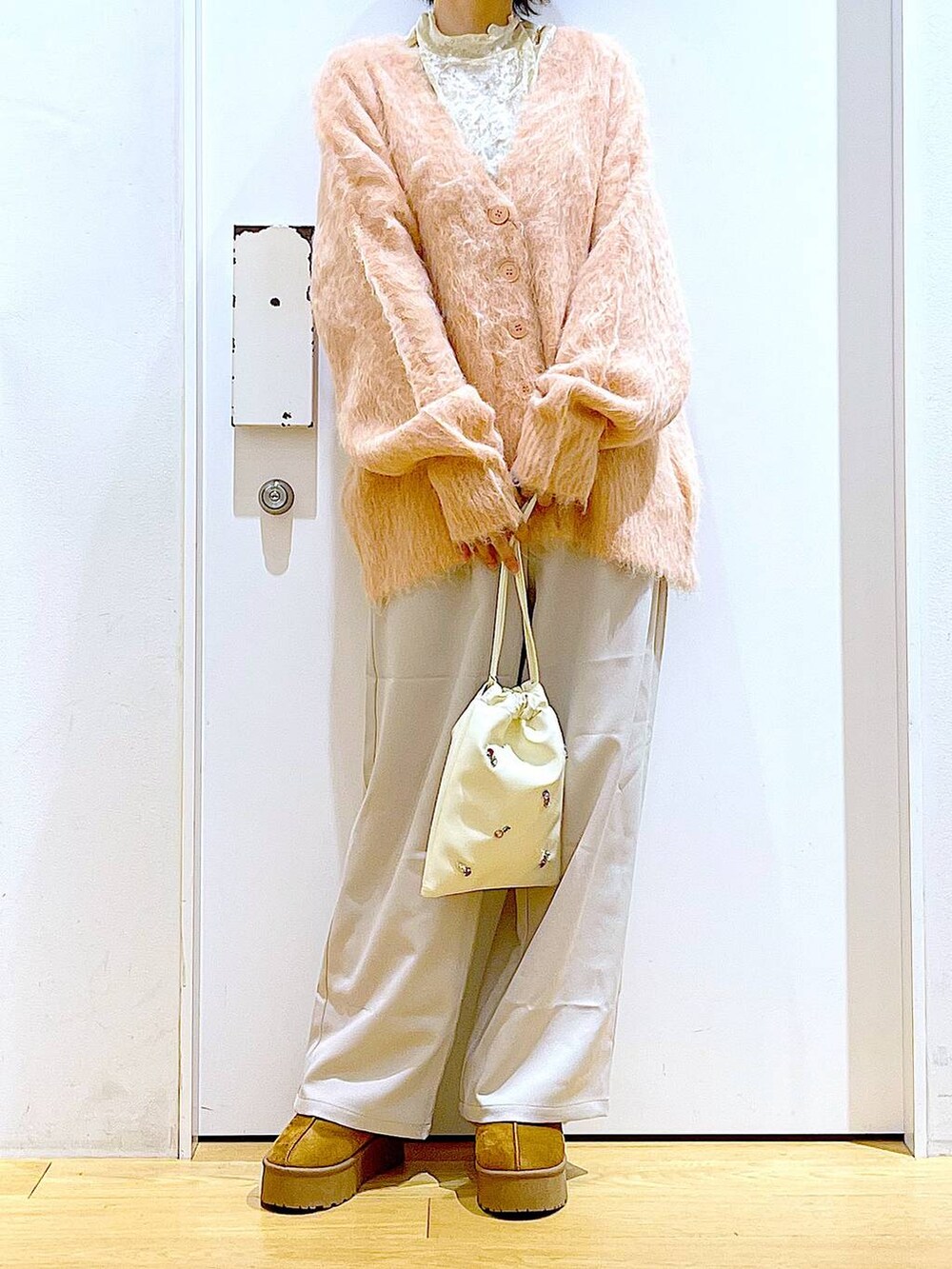 ピンク系のカーディガン/ボレロ、ホワイト系のショルダーバッグ、ホワイト系のTシャツ/カットソーを着用したレディースの冬コーディネートの6枚目の写真