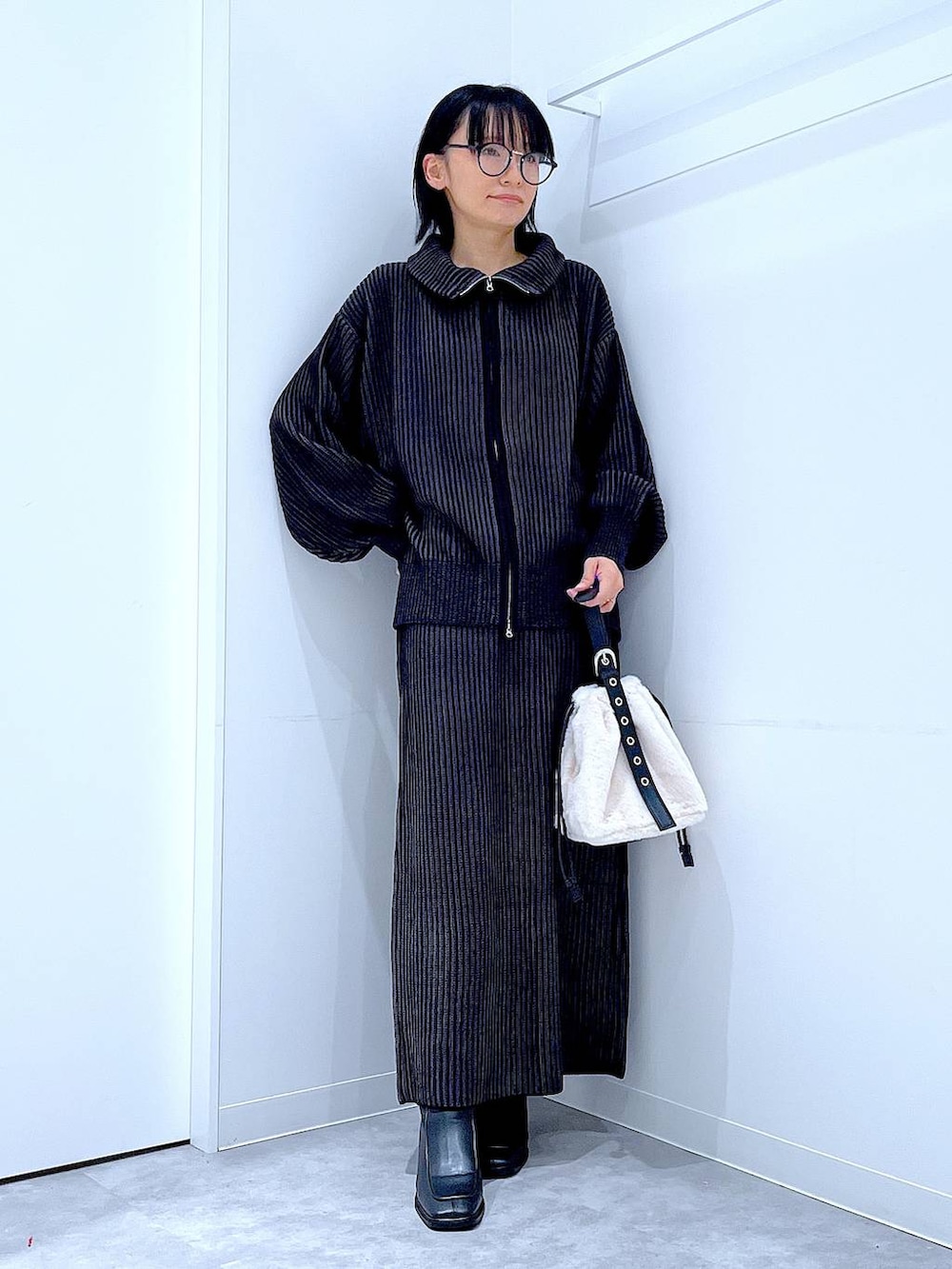 ホワイト系のハンドバッグ、ブラック系のスカート、ブラック系のニット/セーターを着用したレディースの秋コーディネートの2枚目の写真