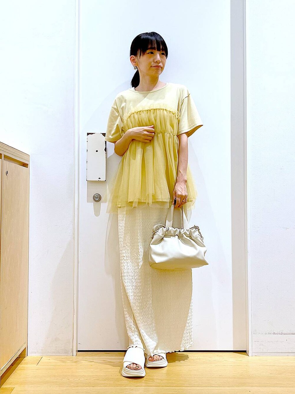 ホワイト系のサンダル、ベージュ系のスカート、イエロー系のTシャツ/カットソーを着用したレディースの夏コーディネートの2枚目の写真