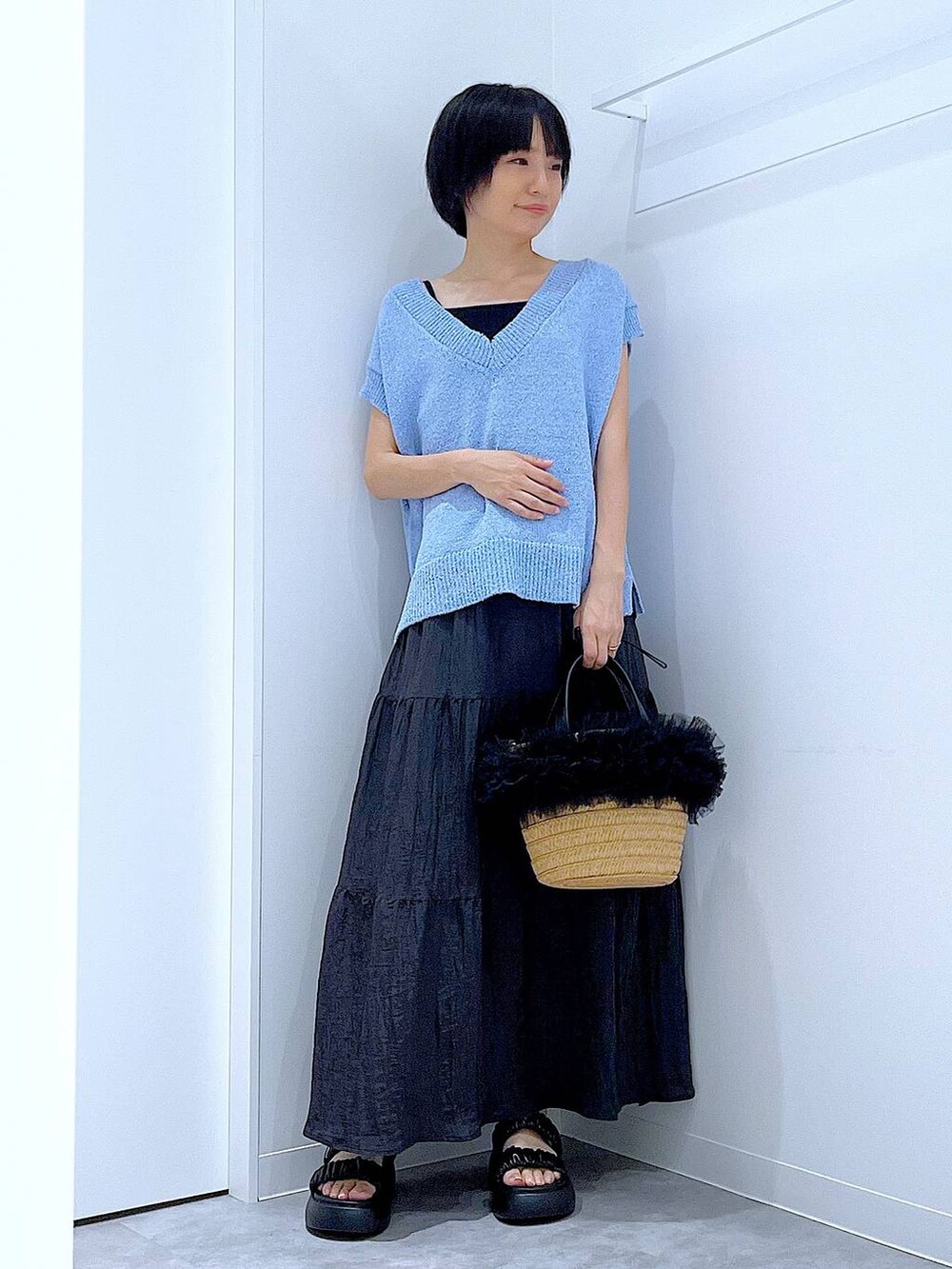 ベージュ系のショルダーバッグ、ブラック系のサンダル、ブルー系のベストを着用したレディースの夏コーディネートの2枚目の写真