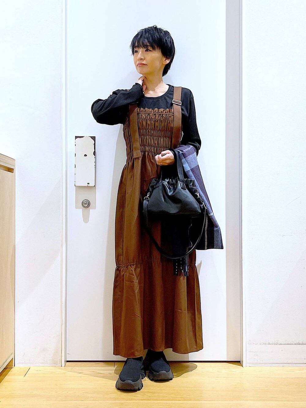 ブラック系のブーツ、ブラウン系のワンピース、ブラック系のショルダーバッグを着用したレディースの冬コーディネートの2枚目の写真