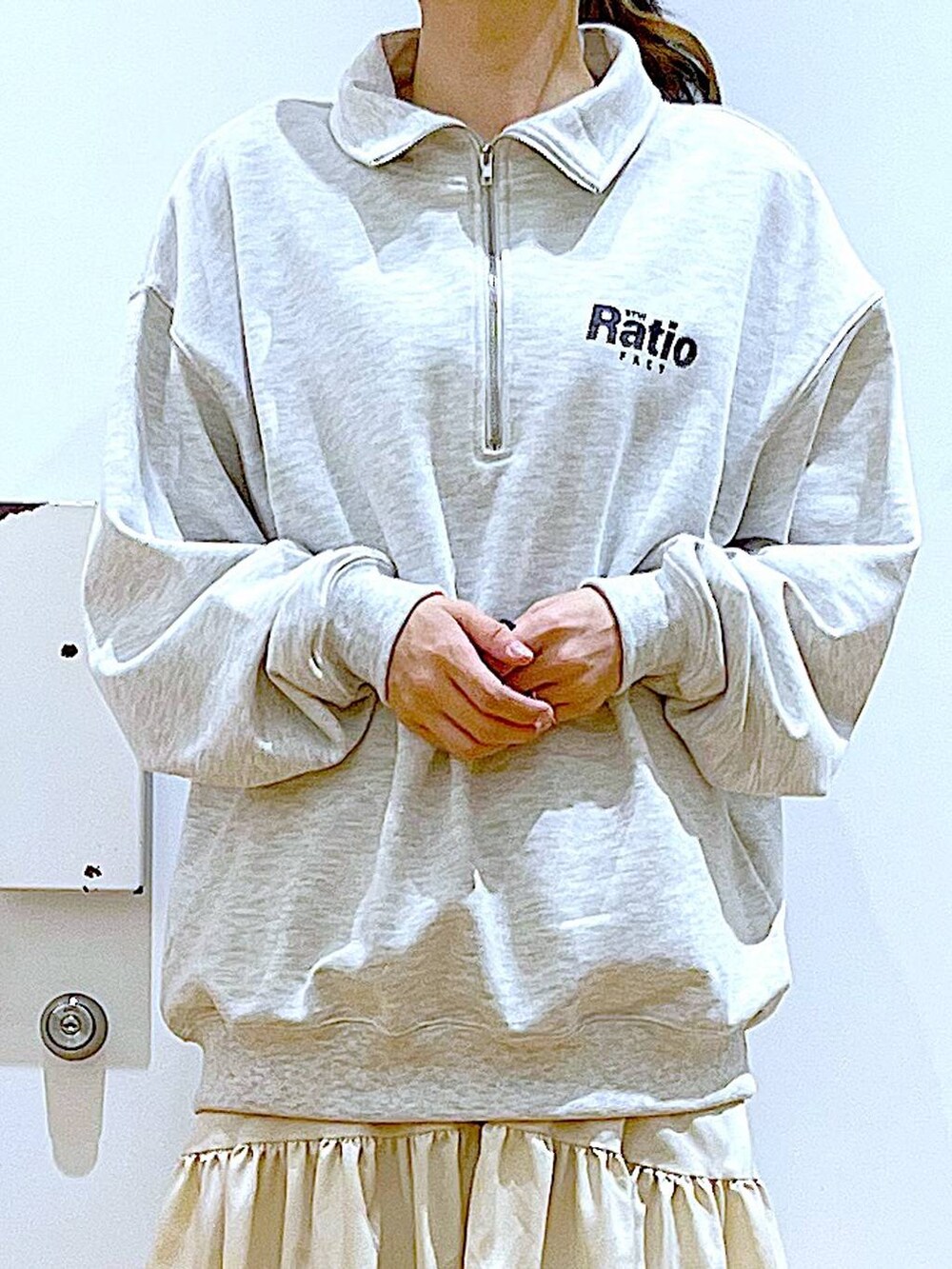 ベージュ系のスウェット、ホワイト系のスカート、ベージュ系のブーツを着用したレディースの春コーディネートの7枚目の写真