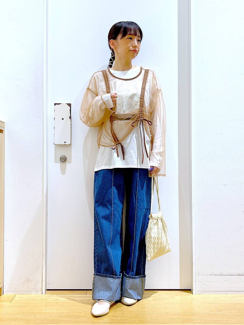 ホワイト系のショルダーバッグ、ホワイト系のパンプス、ブルー系のデニムパンツを着用したレディースの秋コーディネートの2枚目の写真