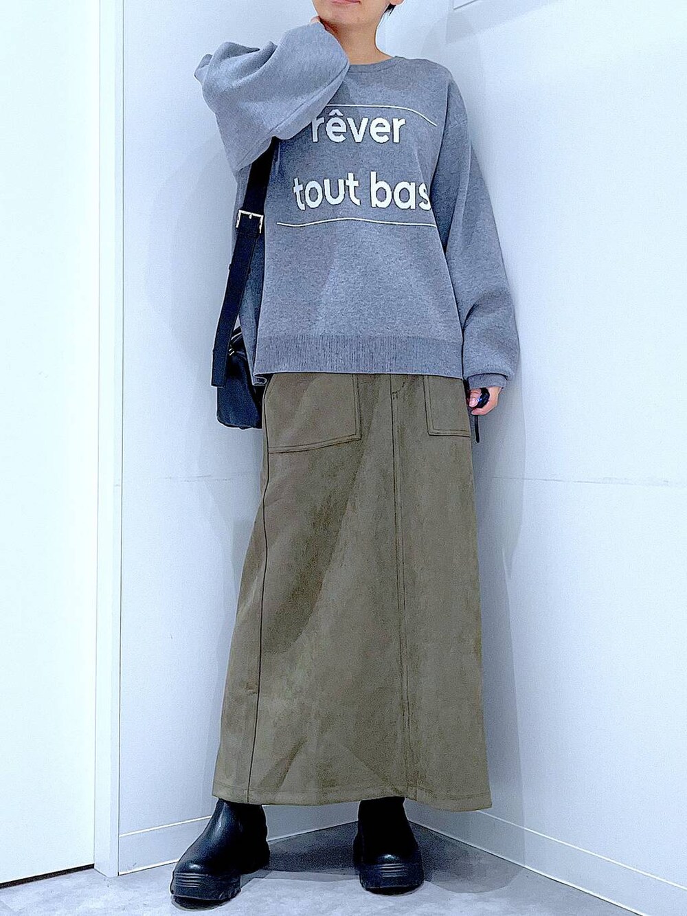 ブラック系のショルダーバッグ、ブラック系のブーツ、グリーン系のスカートを着用したレディースの冬コーディネートの6枚目の写真