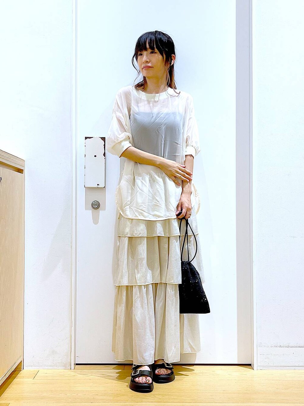 ブラック系のサンダル、ブラック系のショルダーバッグ、ゴールド系のスカートを着用したレディースの夏コーディネートの2枚目の写真