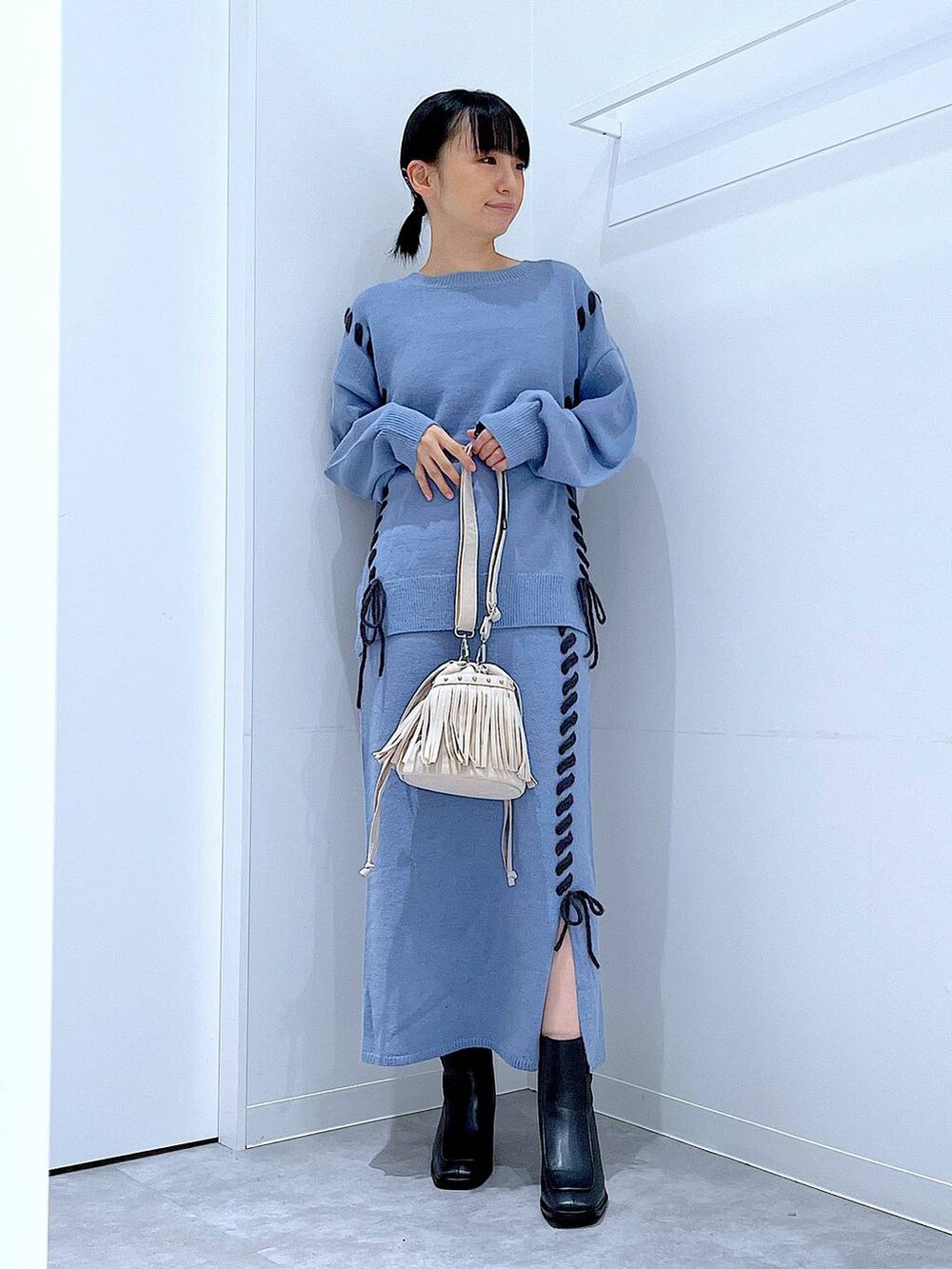 ブルー系のニット/セーター、ブルー系のスカート、ブラック系のブーツを着用したレディースの秋コーディネートの2枚目の写真