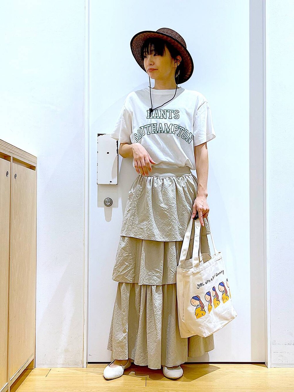 ベージュ系のスカート、ホワイト系のTシャツ/カットソー、その他のトートバッグを着用したレディースの春コーディネートの2枚目の写真