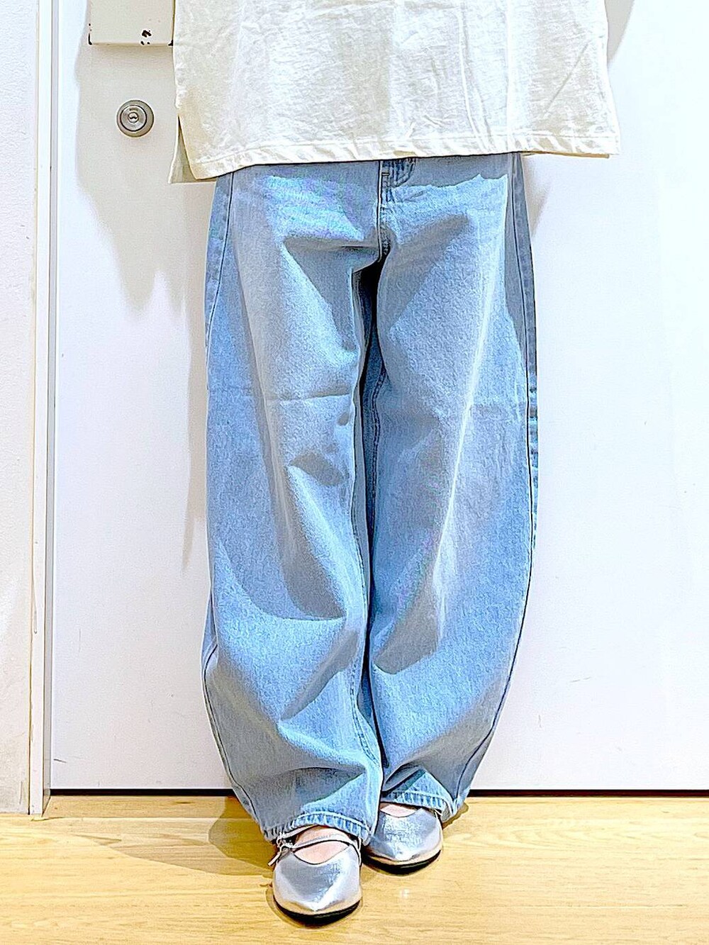 ブラック系のトートバッグ、ブルー系のデニムパンツ、シルバー系のパンプスを着用したレディースの夏コーディネートの8枚目の写真