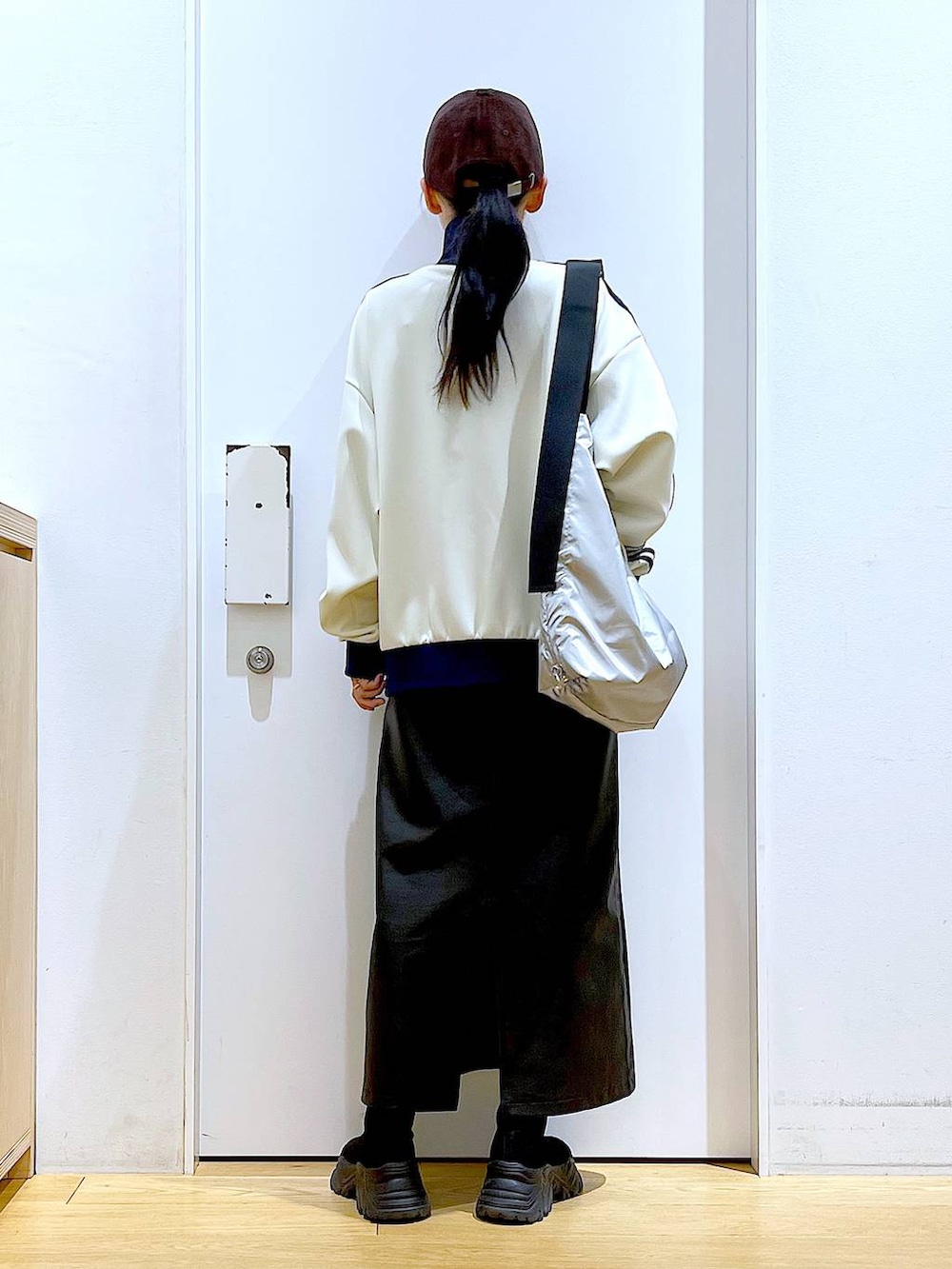 ブラック系のブーツ、ブラック系のスカート、シルバー系のショルダーバッグを着用したレディースの冬コーディネートの5枚目の写真