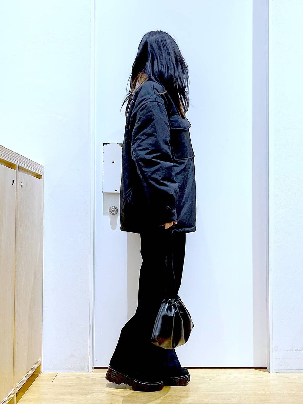 ブラック系のブルゾン、ブラック系のショルダーバッグ、ブラック系のブーツを着用したレディースの冬コーディネートの4枚目の写真