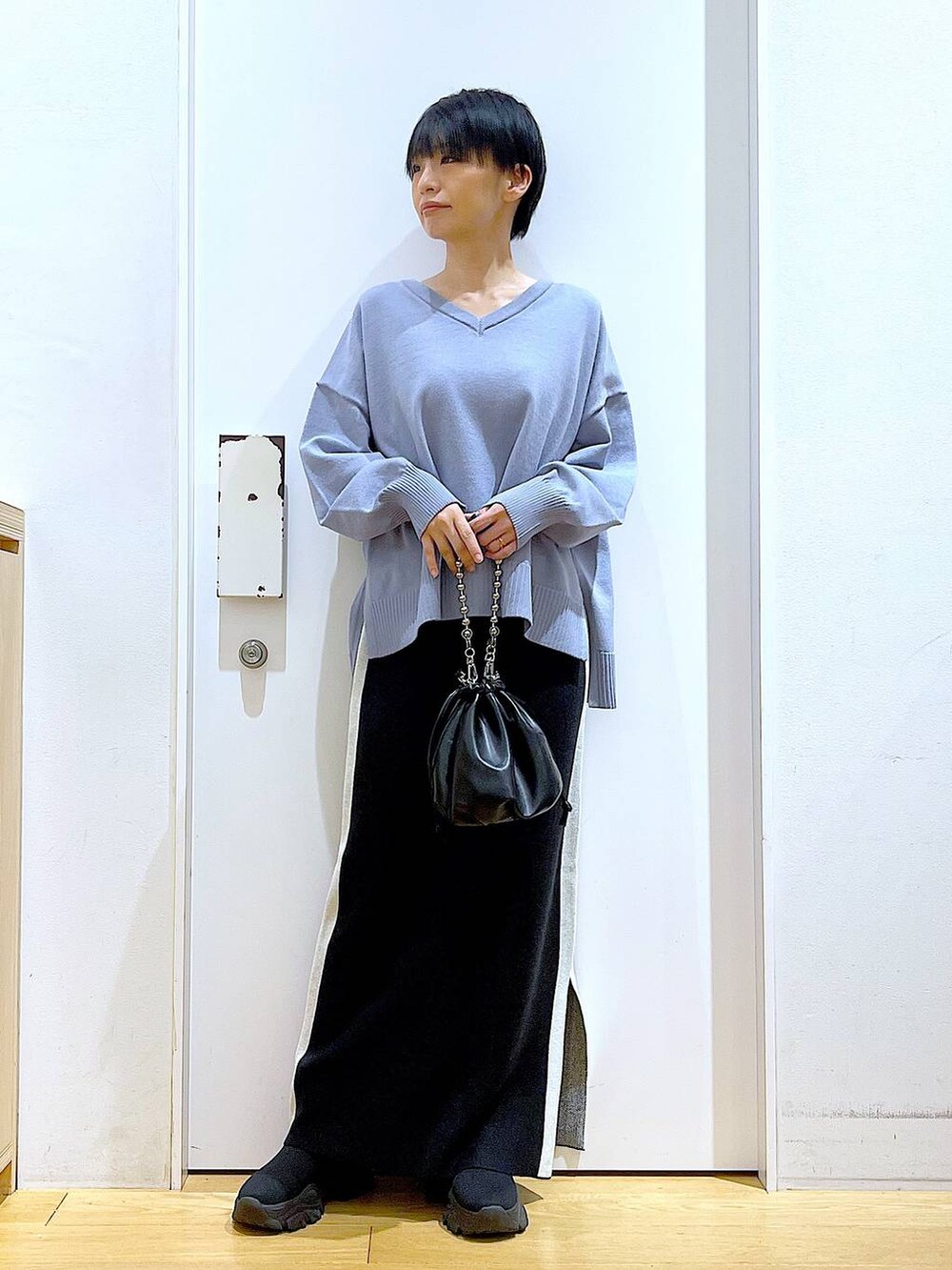 ブラック系のスカート、ブラック系のショルダーバッグ、ブラック系のブーツを着用したレディースの冬コーディネートの2枚目の写真