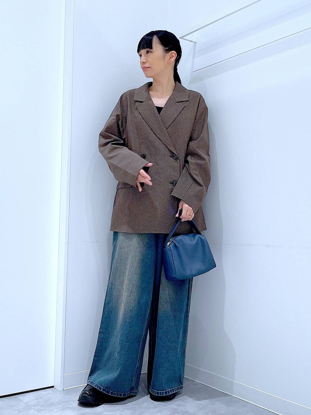 ブラック系のローファー、ブルー系のショルダーバッグ、ブルー系のデニムパンツを着用したレディースの秋コーディネートの2枚目の写真