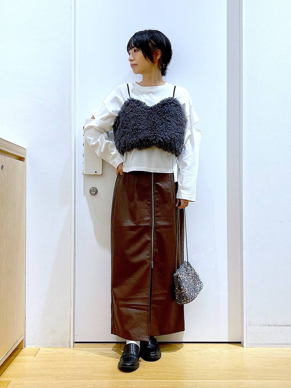 ブラウン系のスカート、グレー系のベスト、ブラック系のローファーを着用したレディースの秋コーディネートの2枚目の写真