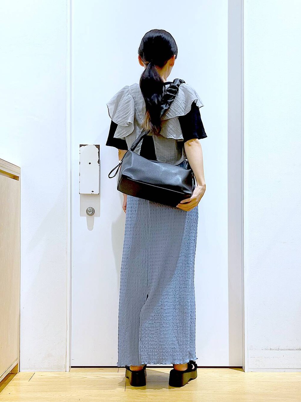 ブラック系のショルダーバッグ、ブルー系のスカート、ブラック系のTシャツ/カットソーを着用したレディースの夏コーディネートの5枚目の写真