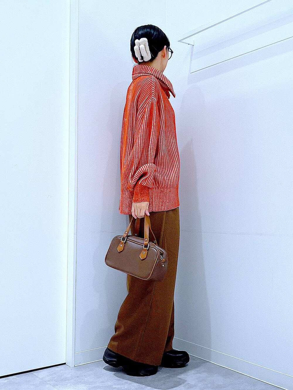 ブラック系のブーツ、オレンジ系のニット/セーター、ブラウン系のその他パンツを着用したレディースの冬コーディネートの4枚目の写真