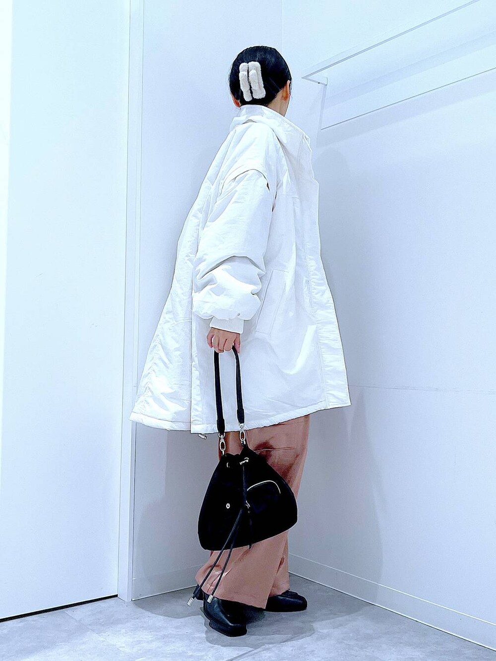 ホワイト系のブルゾン、ブラック系のショルダーバッグ、ブラック系のブーツを着用したレディースの冬コーディネートの4枚目の写真