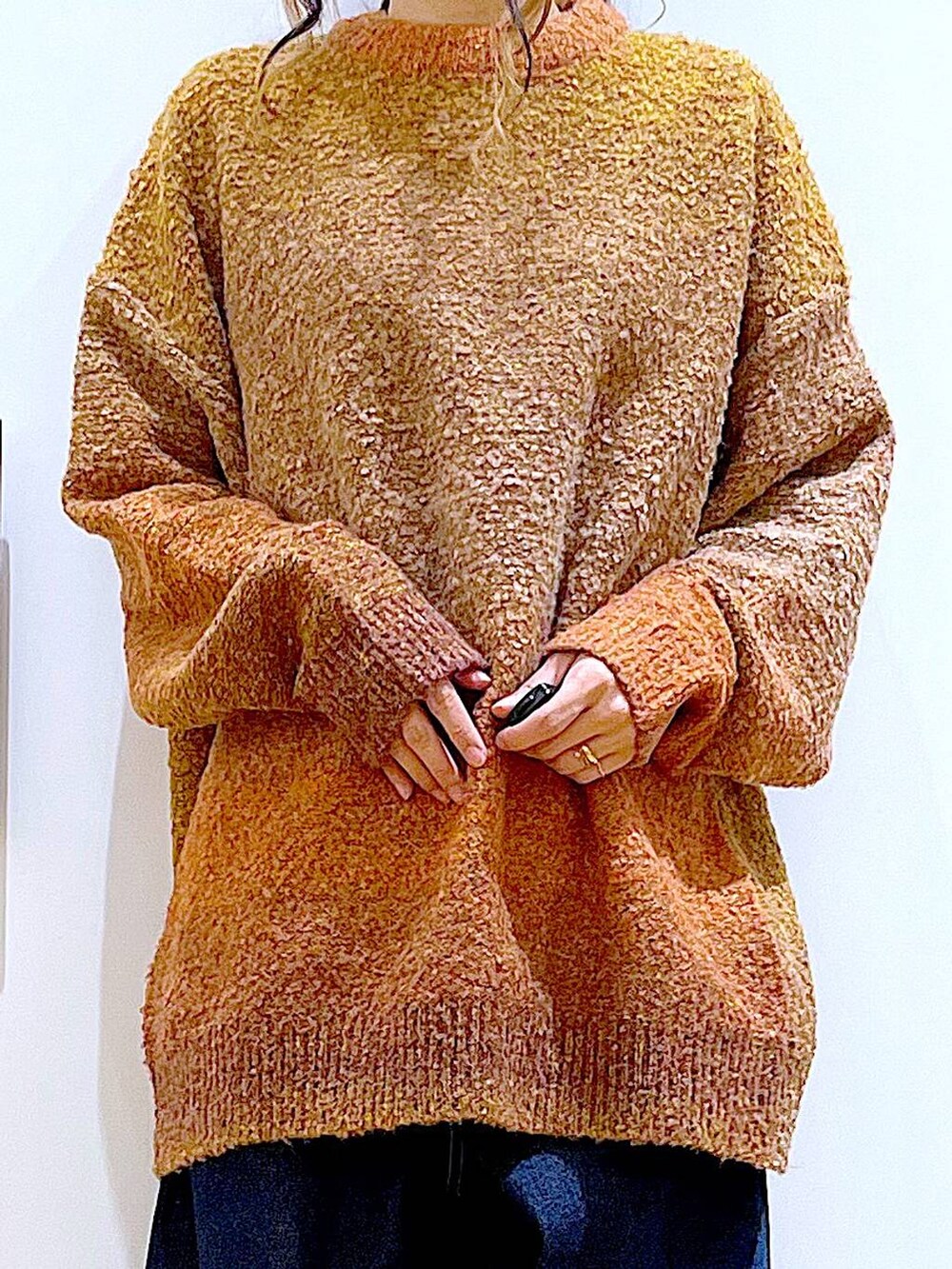 オレンジ系のニット/セーター、ホワイト系のトートバッグ、ベージュ系のブーツを着用したレディースの冬コーディネートの7枚目の写真