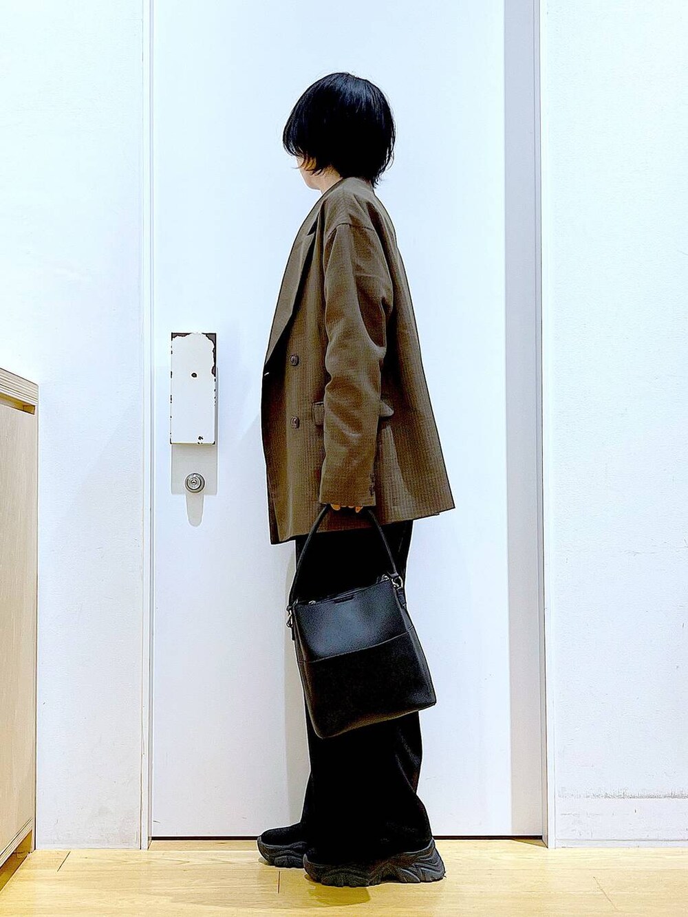 ブラック系のブーツ、ブラック系のショルダーバッグ、ブラウン系のテーラードジャケットを着用したレディースの秋コーディネートの3枚目の写真